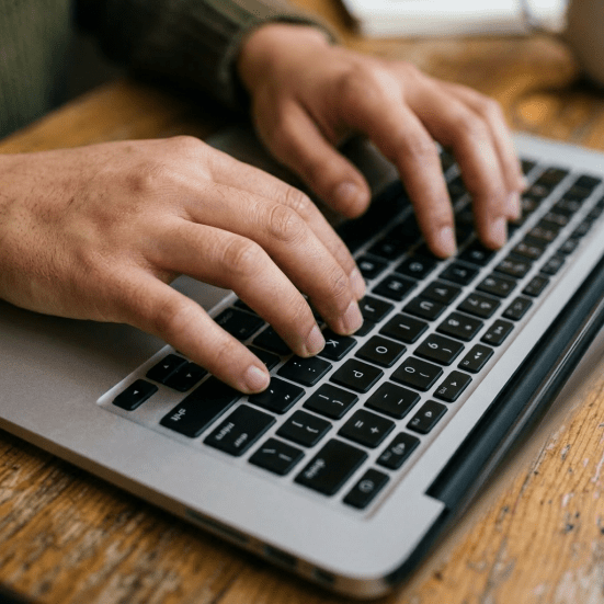 Woman in glasses typing code on laptop in cafe